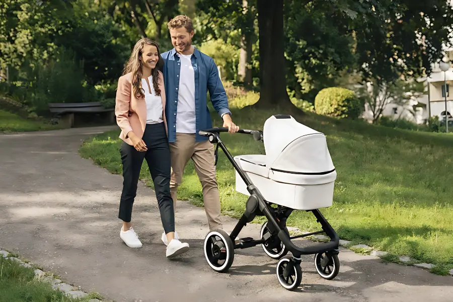 Família passeando no parque com seu filho dentro do carrinho de bebê